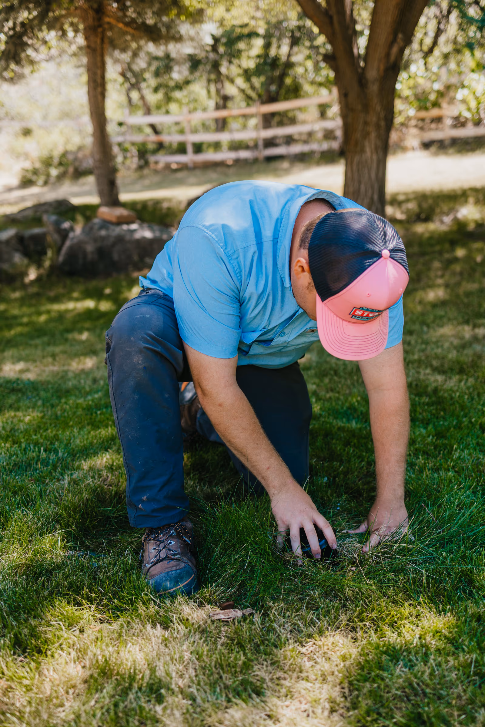 Storm Sprinklers technician kneeling to adjust a pop-up sprinkler head during a lawn tune-up