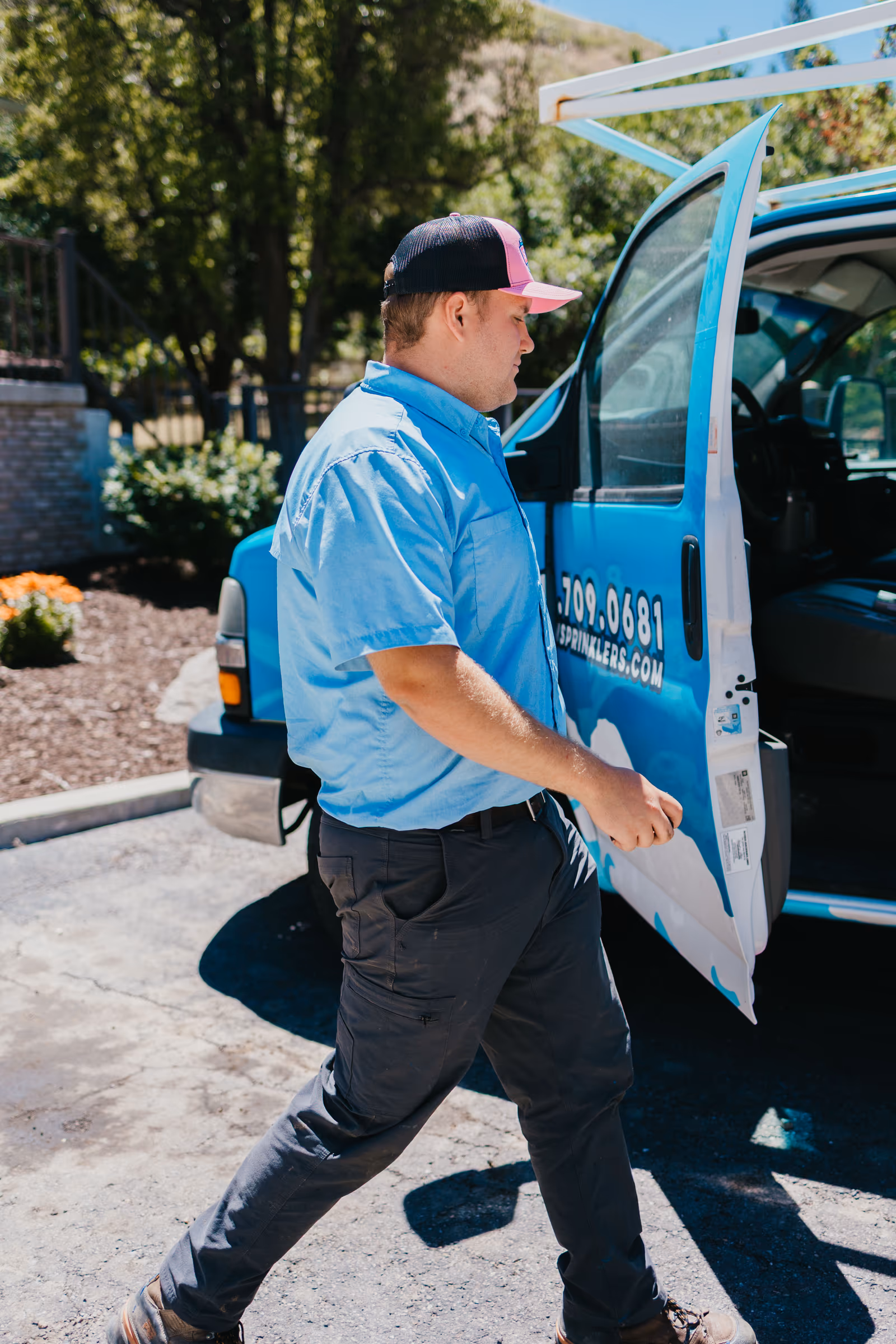 Storm Sprinklers technician walking from a branded blue service van to a commercial irrigation job